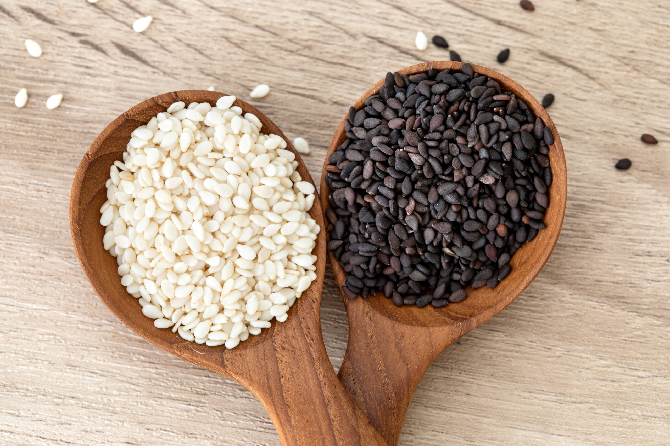 Organic black and white sesame seeds in a wooden spoon promoting heart health and blood pressure control